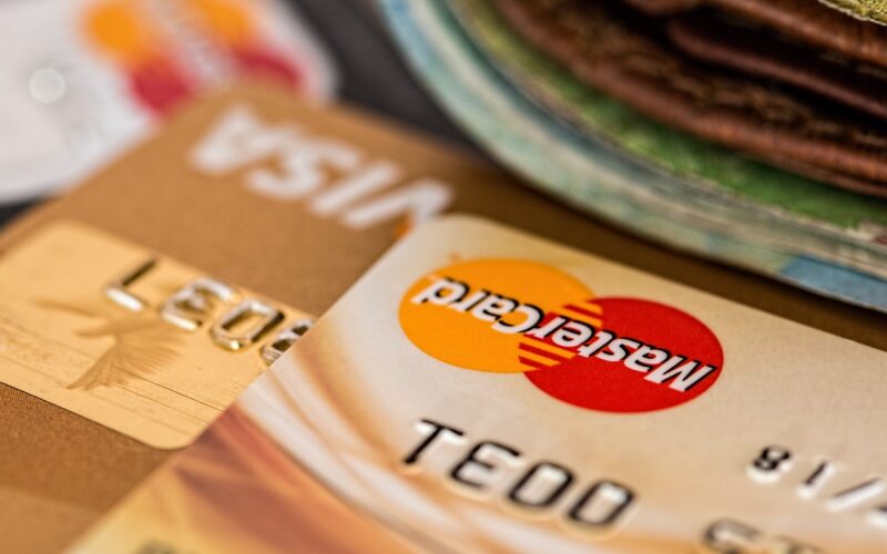 Банковские карты VISA и MasterCard рядом со сложенной пачкой денег