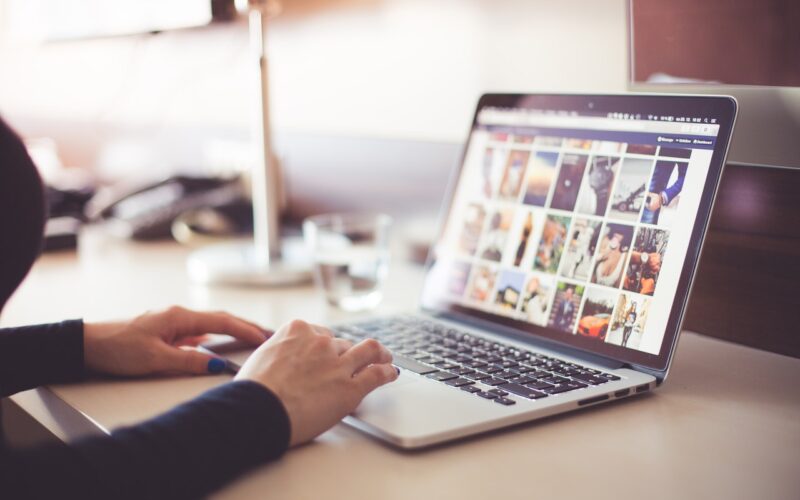 opened laptop with pictures on the screen, woman’s hands on the touchpad